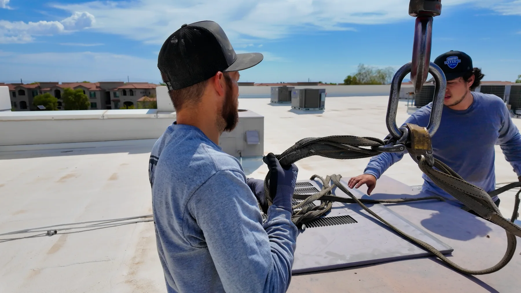 Technicians coordinating crane rigging on a commercial rooftop