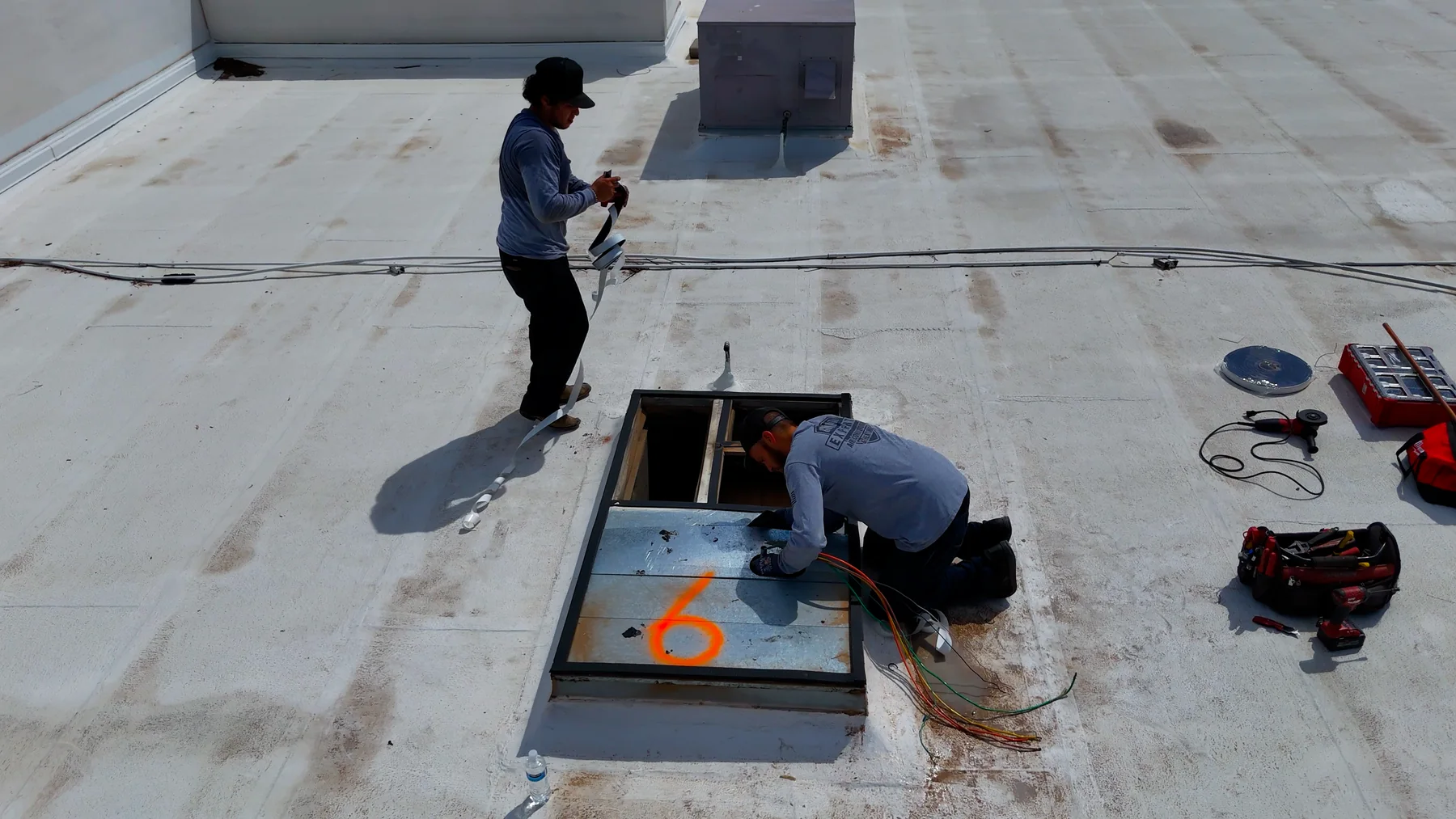 Technicians working at a commercial rooftop HVAC curb