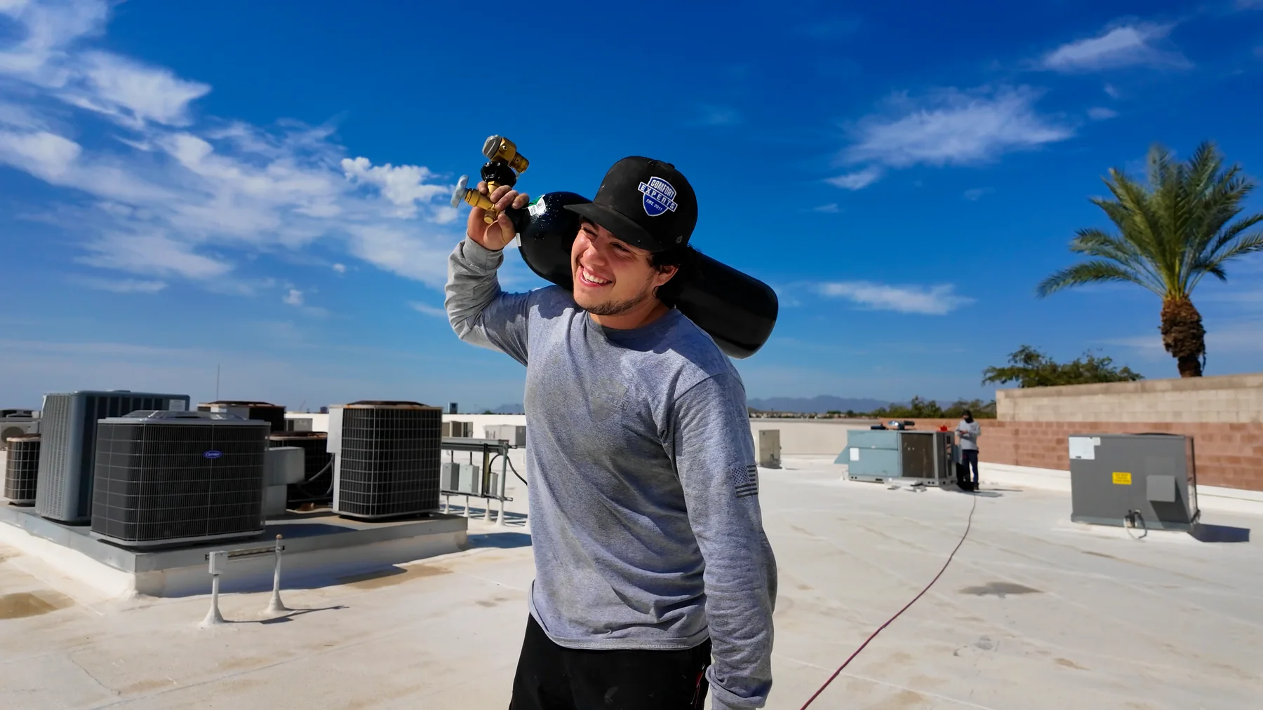 Comfort Experts technician carrying equipment across a commercial rooftop