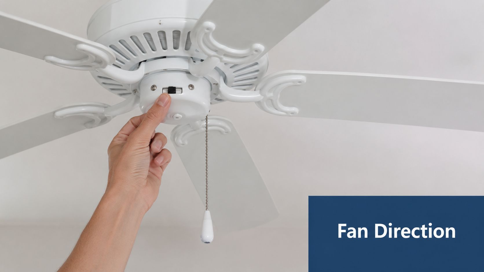 A person adjusting the small black direction switch on a white ceiling fan with their thumb.